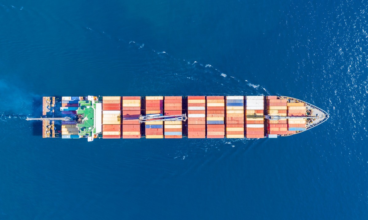 Cargo ship full loaded with containers, blue sea background, top view